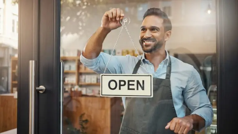 Small business owner flipping the open sign on a shop glass door in the morning